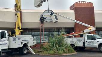 H&H Lighting Maintenance truck being used to repair an exterior pole light in a parking lot